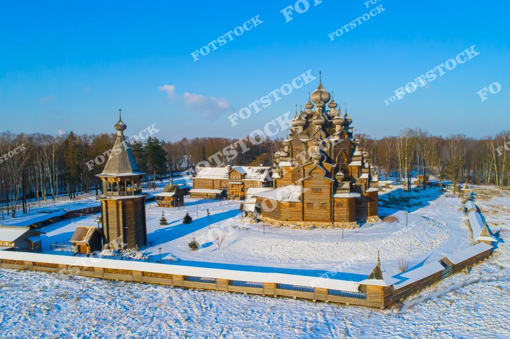Фотография зимней панорамы в Ленинградская область, Россия. На изображении показана Покровская церковь, расположенная в Невский лесопарк недалеко от Санкт-Петербург. Фотоснимок передаёт атмосферу зимнего пейзажа: заснеженный лес, тишина и выразительная деревянная архитектура православного храма. Фото подчёркивает духовные святыни Петербурга, традиции деревянного зодчества и природную красоту окрестностей северной столицы. Иллюстрация отражает тему храмов России и культурного наследия региона.